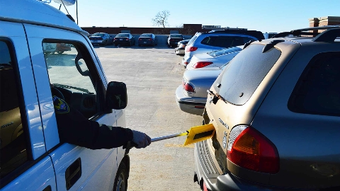 Personal de seguridad de un estacionamiento mirando placas vehiculares